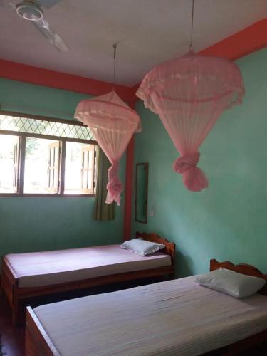 two beds in a bedroom with pink drapes at Wellassa holly day in in Monaragala