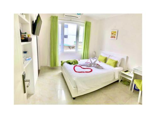 a bedroom with a white bed with green curtains at Hotel La Perle in Hue