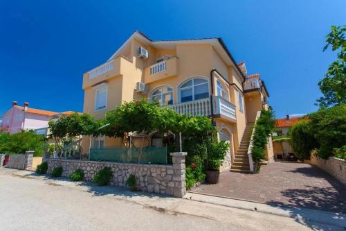 ein großes gelbes Haus mit Bäumen davor in der Unterkunft Studio für 2 Personen  1 Kind ca 40 qm in Šilo, Kvarner Bucht Krk in Šilo