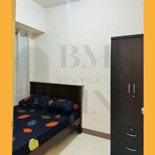 a bedroom with a bed and a black cabinet at Staycation BMR Mnl at Coast Residences in Manila