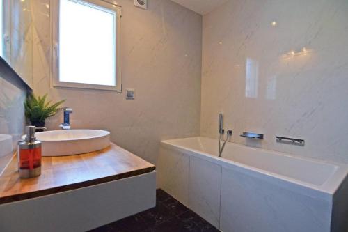 La salle de bains est pourvue d'une grande baignoire, d'un lavabo et d'une baignoire. dans l'établissement MULUA Design & Modern House - Terrasse - Jacuzzi - Parking, à Bidart