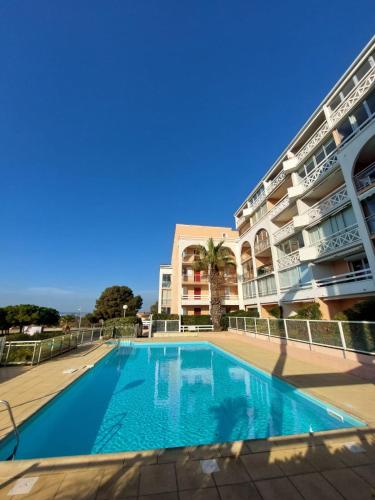une piscine en face d'un grand bâtiment dans l'établissement Appartement 1 chambre, parking et piscine, à Sète