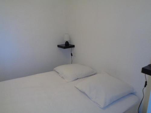 une chambre avec un lit avec deux oreillers dessus dans l'établissement Appartement 1 chambre, parking et piscine, à Sète