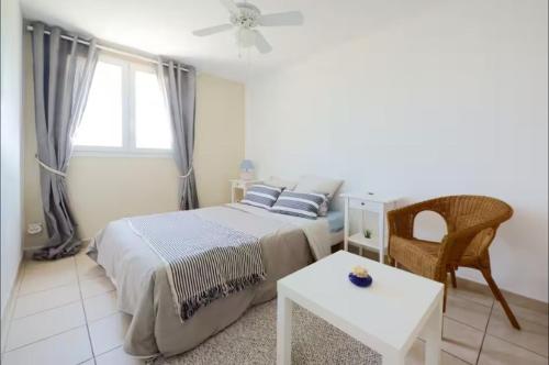a bedroom with a bed and a table and a window at Jolie Chambre chaleureuse in Marseille