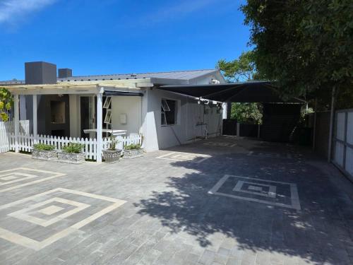 a house with a white fence and a patio at Hartenbos Breakaway - LightHouse Cottage in Mossel Bay