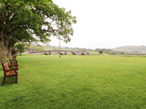 two benches in a field with a bridge in the background at The Old Cobblers in Skipton