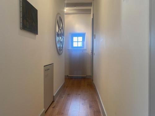 an empty hallway with a window and a clock on the wall at La Petite Campagne in Lonay