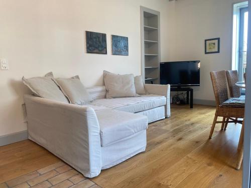 a living room with a white couch and a television at La Petite Campagne in Lonay