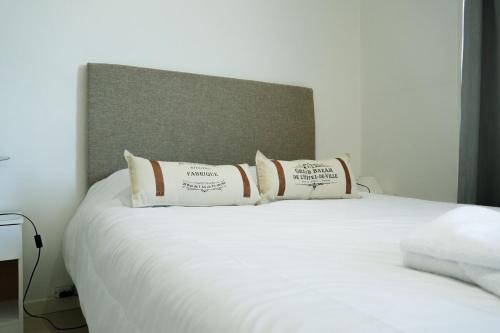 a white bed with three pillows on top of it at Ideal si venis por trabajo, con cochera in Benavídez