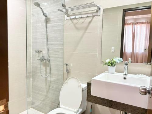 a bathroom with a toilet and a sink and a shower at Family-Friendly Condo Unit in Lapu Lapu City