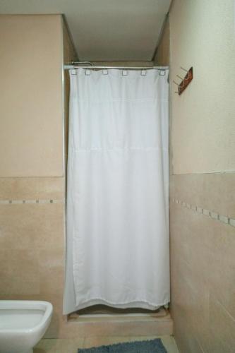 a white shower curtain in a bathroom with a toilet at Ideal si venis por trabajo, con cochera in Benavídez