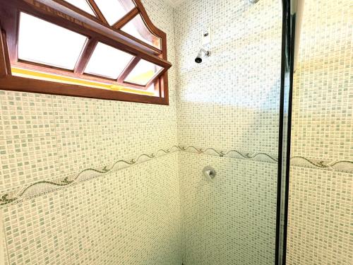 a bathroom with a glass shower with a window at Terra do Sol Pousada e Hostel in Porto Seguro