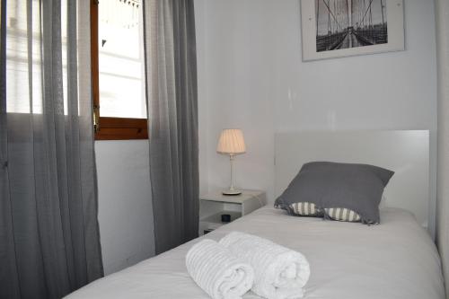 a bedroom with a bed with white sheets and a window at Zentral Gelegene Wohnung in Cómpeta