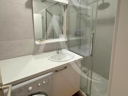 une salle de bain avec un lavabo et une douche en verre dans l'établissement quartier plage de la corniche 1 chambre parking, à Sète
