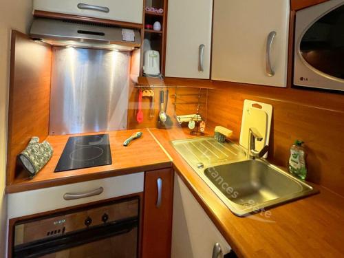 une petite cuisine avec un évier et une cuisinière dans l'établissement quartier plage de la corniche 1 chambre parking, à Sète