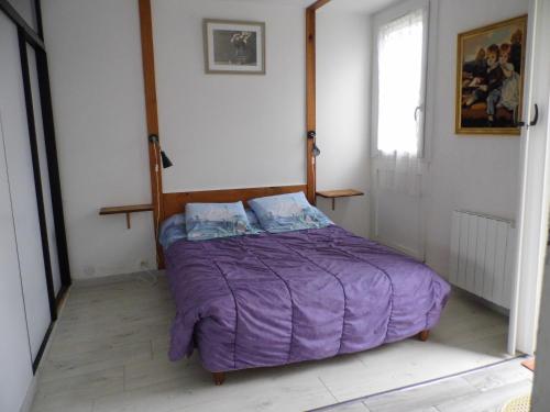 a bedroom with a bed with a purple comforter at le petit marais n1 in Nouan-le-Fuzelier