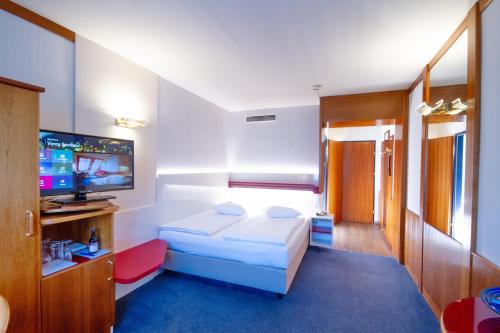 a hotel room with a bed and a flat screen tv at Vienna Sporthotel in Vienna