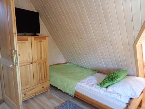 a small bedroom with a bed and a tv on a cabinet at Natura Bukowina Tatrzańska in Bukowina Tatrzańska