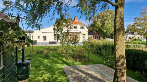 a white house with a tree in the yard at B&B Moleneind Pieterburen in Pieterburen
