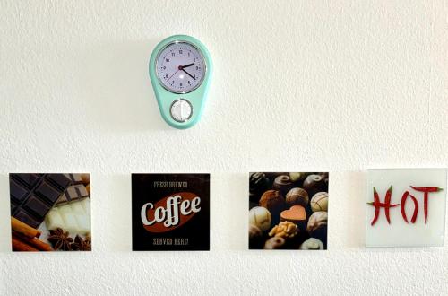 a clock hanging on a wall with pictures of coffee at Lütte Wulke 8, wo Träume Weite finden in Wunstorf