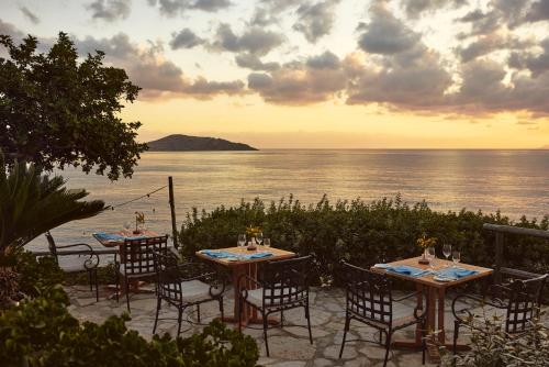 a group of tables and chairs with a view of the ocean at Aquila Elounda Village Resort, Suites & Spa in Elounda