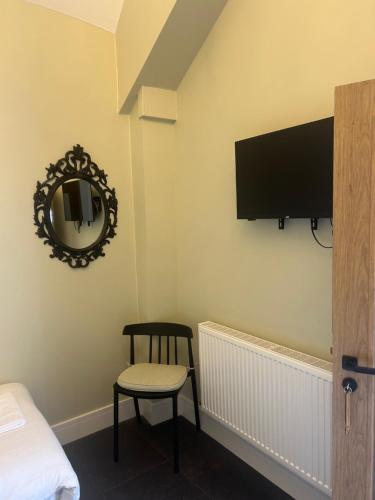 ein Zimmer mit einem Fernseher, einem Stuhl und einem Spiegel in der Unterkunft The George & Dragon Tearoom Accommodation Felton in Felton