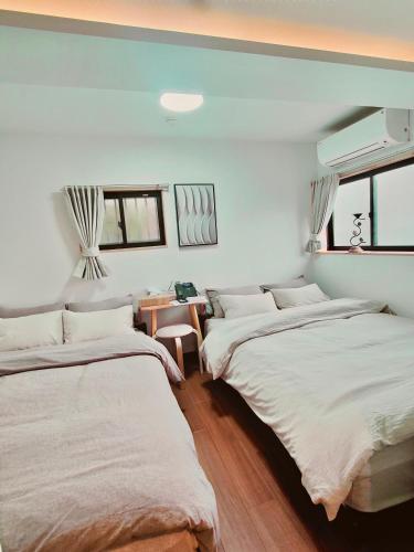two beds in a room with white walls and windows at Moon Hotel in Tokyo