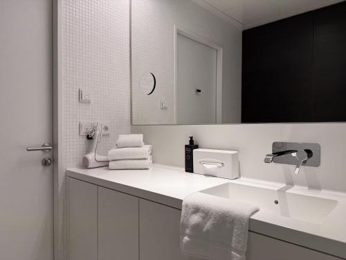 une salle de bain blanche avec un lavabo et un miroir dans l'établissement Luxury City Apartment with Skyline View, à Vienne