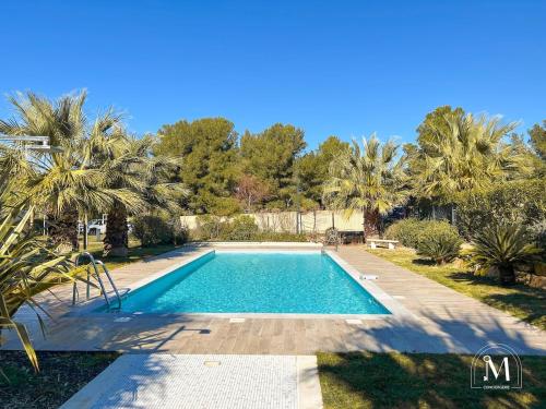une piscine dans une cour avec des palmiers dans l'établissement Appartement cosy dans résidence avec piscine, à Sanary-sur-Mer