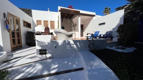 a white house with white walls and blue chairs at Appartement Casa Hibisco Mit Schönem Garten in Uga