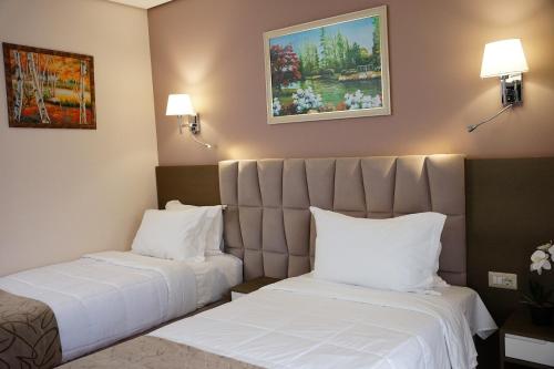 two beds in a hotel room with white sheets and pillows at Doanesia Premium Hotel & Spa in Tirana