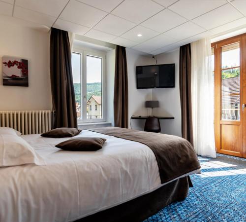a bedroom with a large bed and a large window at Hotel Le Bellevue in Saint-Hippolyte