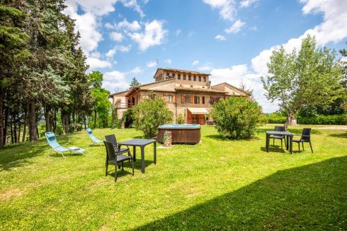 a yard with tables and chairs in front of a house at Appartamento Maria in San Gimignano