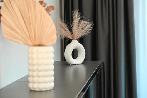 two vases sitting on top of a table with feathers at Kintų Perlas Vila keturiems VIII in Kintai