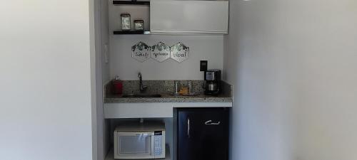a small kitchen with a sink and a microwave at Chalé de alto padrão em condomínio in Santa Rita do Sapucaí
