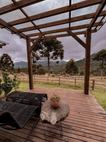 a wooden deck with a bench and a table at Monte Sião Château in Urubici