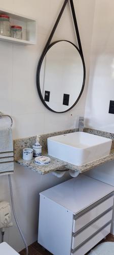 a bathroom with a white sink and a mirror at Chalé de alto padrão em condomínio in Santa Rita do Sapucaí