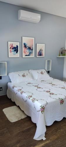 a white bed in a bedroom with pictures on the wall at Chalé de alto padrão em condomínio in Santa Rita do Sapucaí