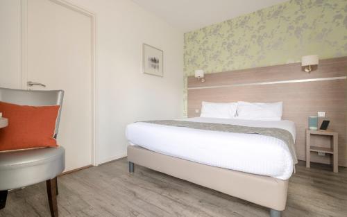 a bedroom with a large bed and a chair at The Originals City, le Beaujoire, Nantes - FACE Parc Expo et FACE Stade Beaujoire in Nantes
