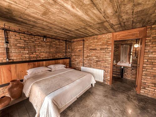 a bedroom with a large bed in a brick wall at Monte Sião Château in Urubici