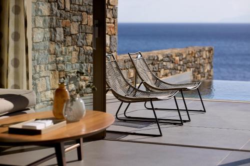 two chairs and a coffee table on a balcony at Aquila Elounda Village Resort, Suites & Spa in Elounda