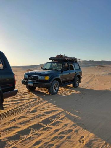 a suv parked on the sand in the desert at White Desert Safari With Camping in Bawiti