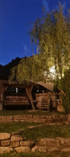 a house with a tree and a wooden structure at Havva in Călimăneşti