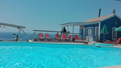 a swimming pool with red chairs and a blue building at Casa de Blue in Lourdhata