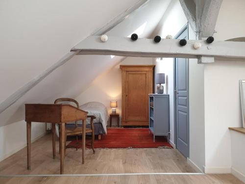 Cette chambre mansardée comprend un bureau et un lit. dans l'établissement Gîtes Auversois, à Auvers-Saint-Georges