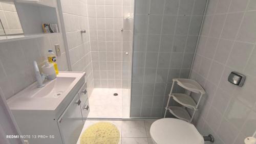 ein Badezimmer mit Dusche, Toilette und Waschbecken in der Unterkunft Bertioga pé na areia in Bertioga