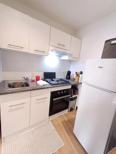 une cuisine avec des armoires blanches et un réfrigérateur blanc dans l'établissement Maison de village au centre de Thuir jusqu'à 5 personnes et 1 bébé, à Thuir