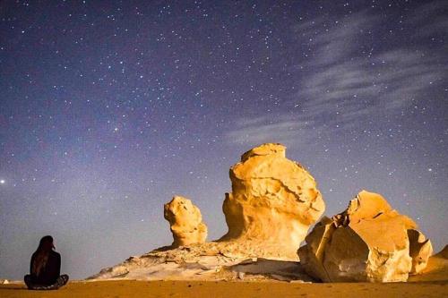 a man sitting in the desert under a starry sky at White Desert Safari With Camping in Bawiti