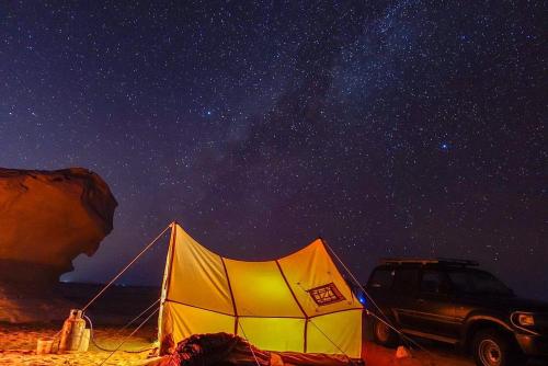 a tent and a car on a beach at night at White Desert Safari With Camping in Bawiti