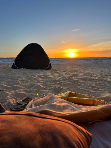 a sunset on a beach with a tent in the sand at White Desert Safari With Camping in Bawiti